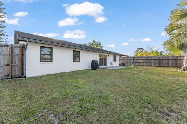 rear view of house with a fenced backyard, a patio area, concrete block siding, and a yard