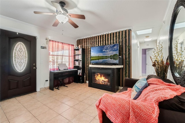 living room with light tile patterned floors, a large fireplace, a ceiling fan, and ornamental molding