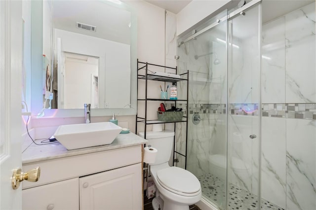 bathroom with a marble finish shower, visible vents, toilet, and vanity