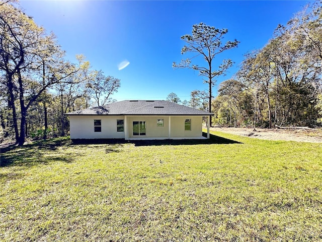 rear view of house with a lawn and stucco siding