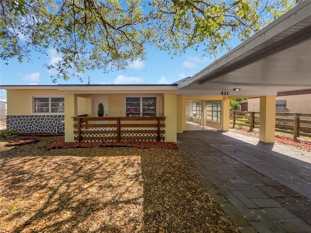 rear view of house with stucco siding and fence