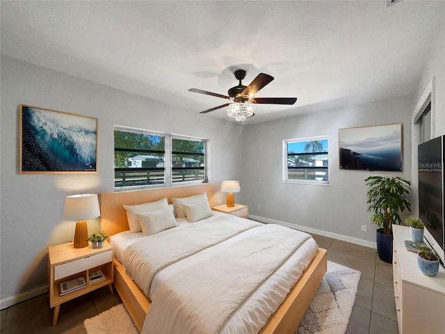 tiled bedroom featuring baseboards, multiple windows, and ceiling fan