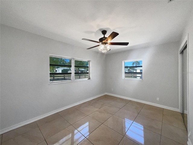 unfurnished bedroom featuring tile patterned flooring, multiple windows, baseboards, and ceiling fan