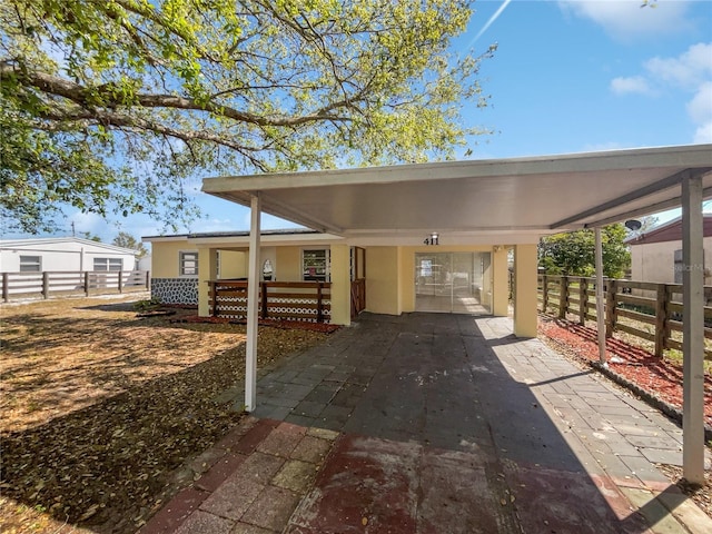 exterior space with a carport, driveway, and fence