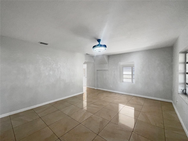 tiled empty room with visible vents and baseboards