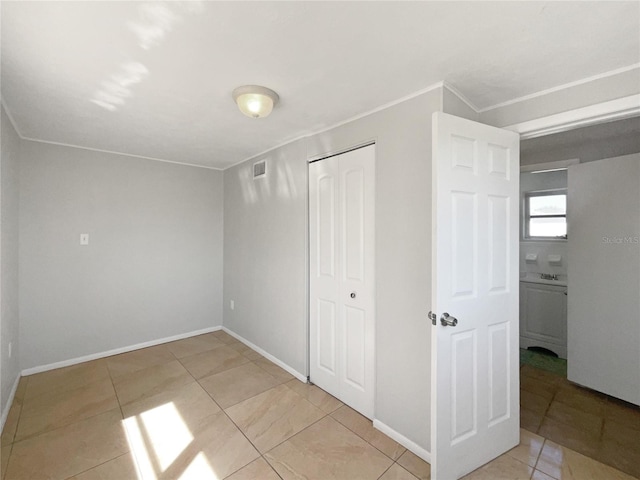 unfurnished bedroom with visible vents, a closet, crown molding, light tile patterned floors, and baseboards