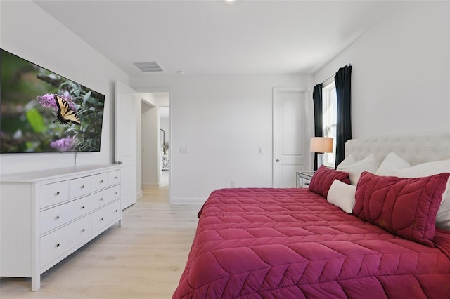 bedroom featuring light wood-style floors, visible vents, and baseboards