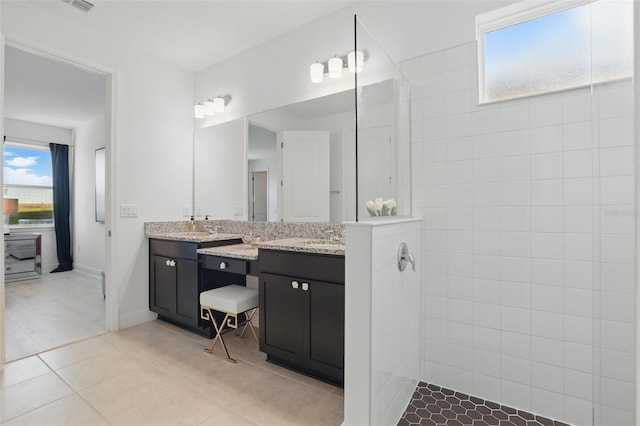 full bathroom with baseboards, double vanity, a sink, a walk in shower, and tile patterned floors