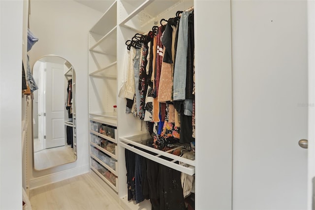 spacious closet with wood finished floors and arched walkways