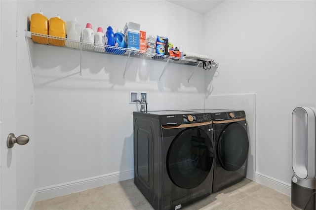 clothes washing area with washing machine and clothes dryer, laundry area, tile patterned flooring, and baseboards