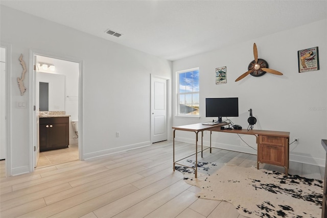 office space featuring light wood finished floors, visible vents, a ceiling fan, and baseboards