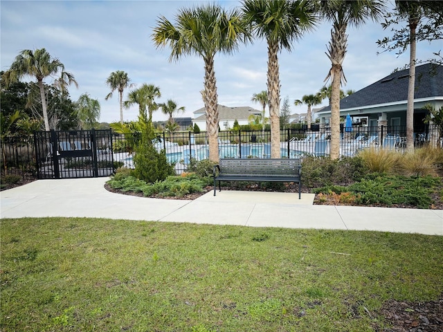 view of home's community featuring a swimming pool, a lawn, and fence