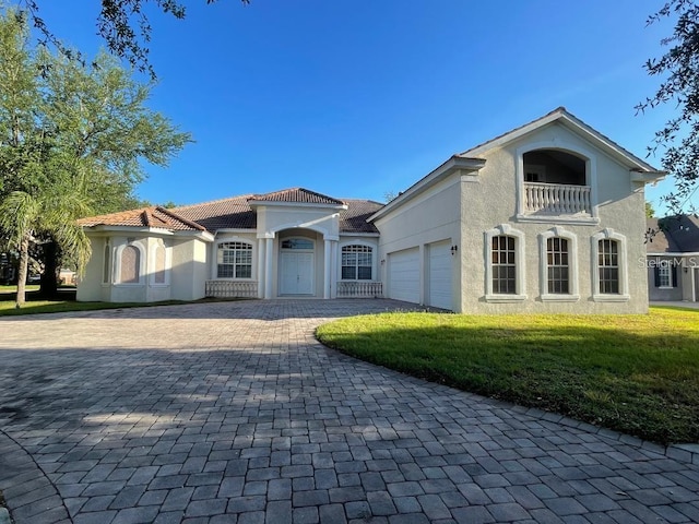 mediterranean / spanish-style house featuring a balcony, an attached garage, stucco siding, a tiled roof, and decorative driveway