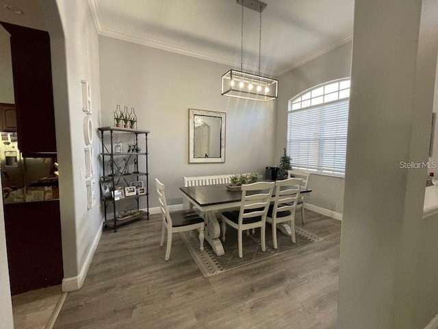 dining room with crown molding, wood finished floors, and baseboards