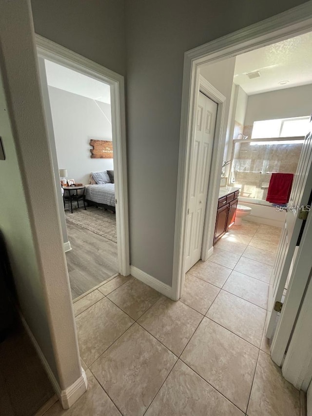 hallway featuring baseboards and light tile patterned flooring