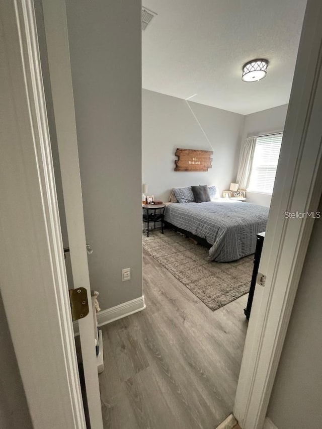 bedroom featuring visible vents, baseboards, and wood finished floors