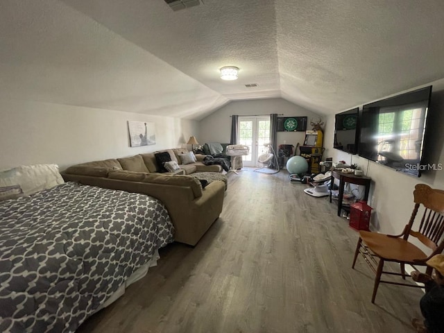 bedroom with visible vents, lofted ceiling, a textured ceiling, and wood finished floors