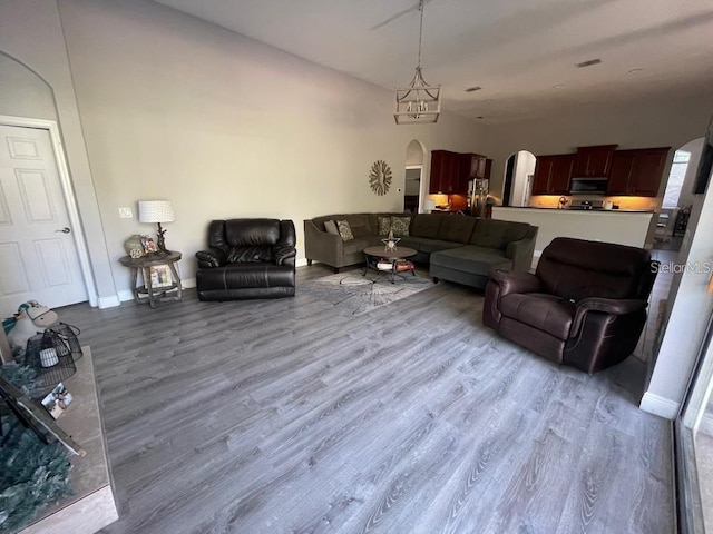 living room featuring baseboards, arched walkways, visible vents, and wood finished floors