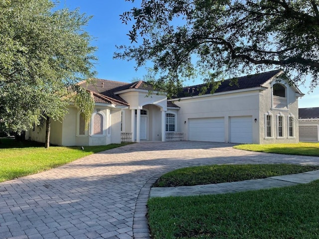 view of front facade featuring stucco siding, decorative driveway, a front yard, a garage, and a tiled roof