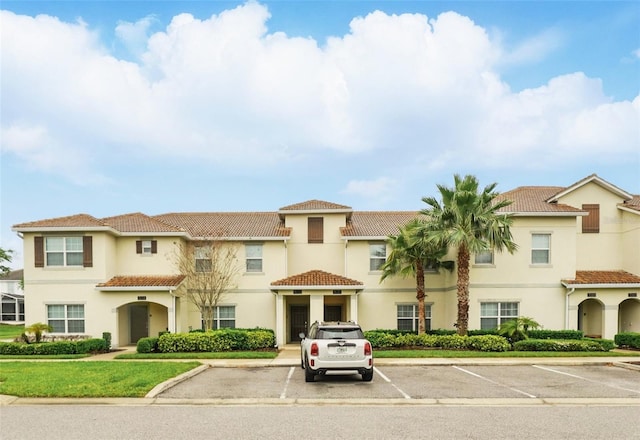 view of front of property featuring stucco siding, uncovered parking, and a tiled roof