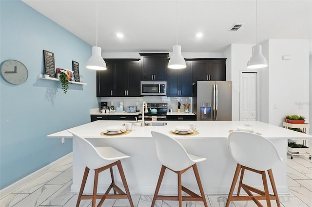 kitchen featuring stainless steel appliances, light countertops, a kitchen bar, marble finish floor, and backsplash