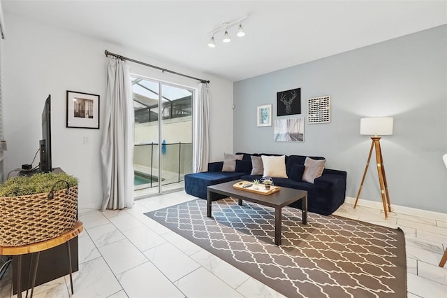 living area with track lighting, marble finish floor, and baseboards