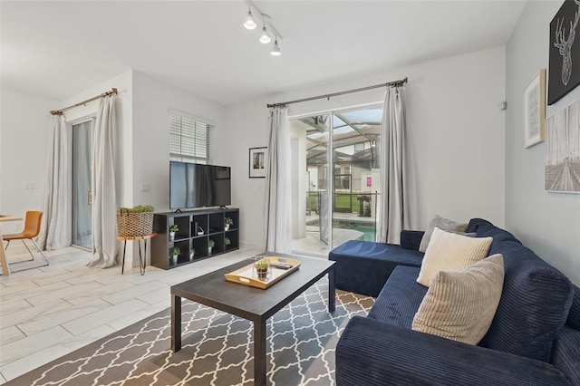 living area featuring plenty of natural light, marble finish floor, and track lighting