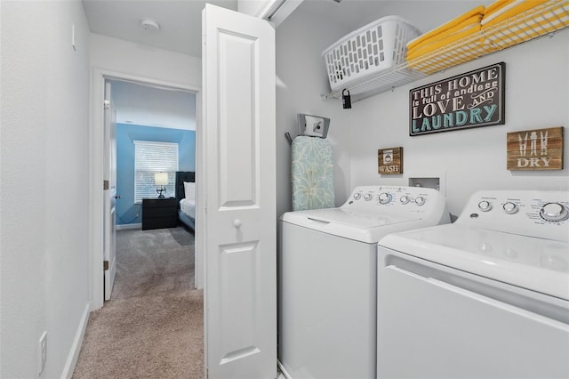 washroom featuring baseboards, light carpet, washing machine and dryer, and laundry area