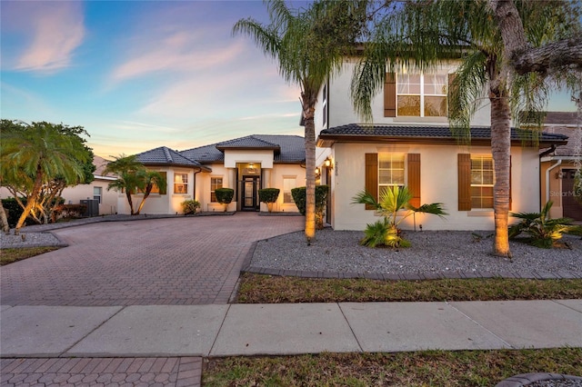 view of front of property featuring stucco siding, a tile roof, and decorative driveway