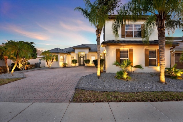 view of front facade featuring decorative driveway, a tile roof, and stucco siding