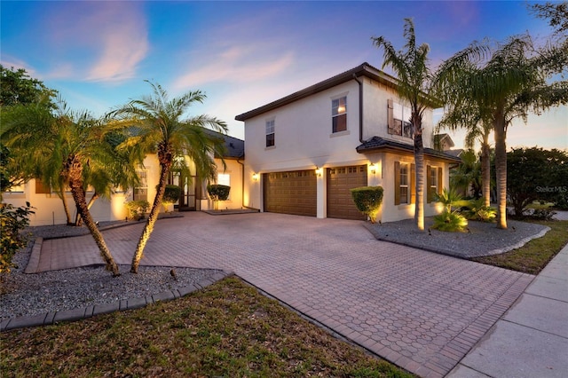 view of front of property with stucco siding, decorative driveway, and a garage