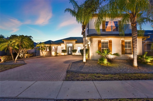 view of front of property featuring stucco siding, a tile roof, and decorative driveway