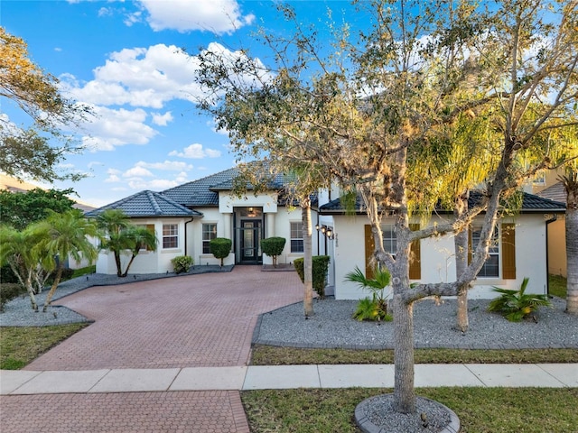 view of front of property with stucco siding, a tiled roof, and decorative driveway