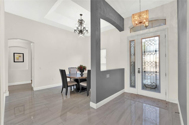 entrance foyer featuring a chandelier, arched walkways, and baseboards