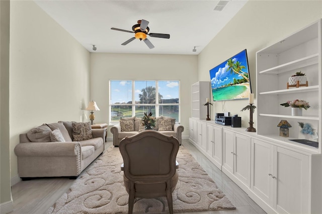 living area with light wood finished floors, visible vents, baseboards, and a ceiling fan