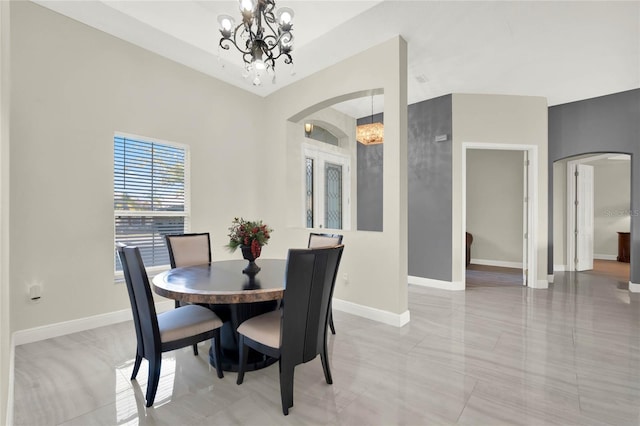 dining area featuring arched walkways, baseboards, and an inviting chandelier