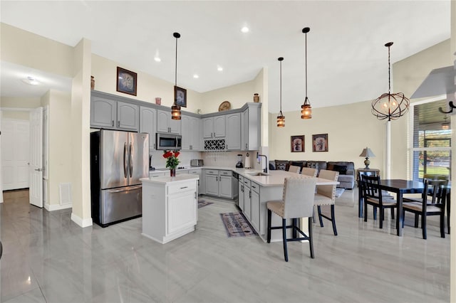 kitchen with visible vents, gray cabinetry, a sink, stainless steel appliances, and a peninsula