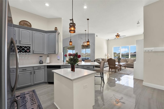 kitchen featuring gray cabinets, open floor plan, a center island, appliances with stainless steel finishes, and light countertops