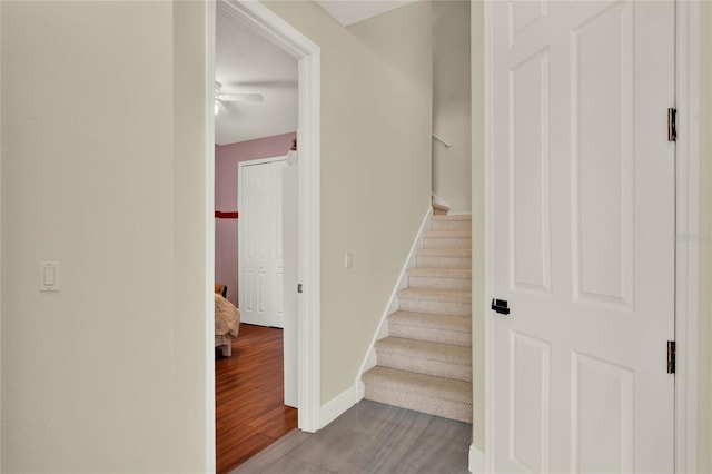 stairway with baseboards, wood finished floors, and a ceiling fan