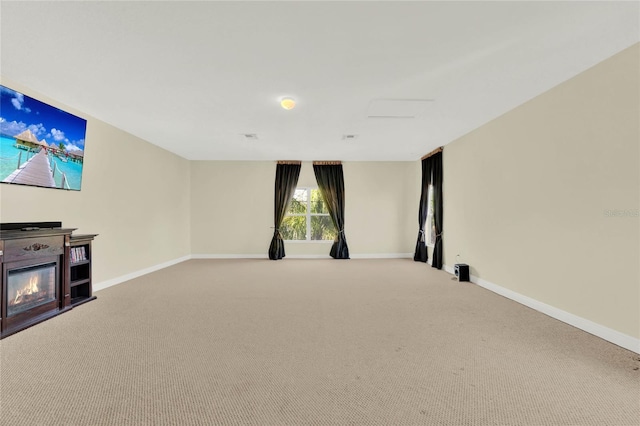 unfurnished living room with baseboards, carpet, and a glass covered fireplace