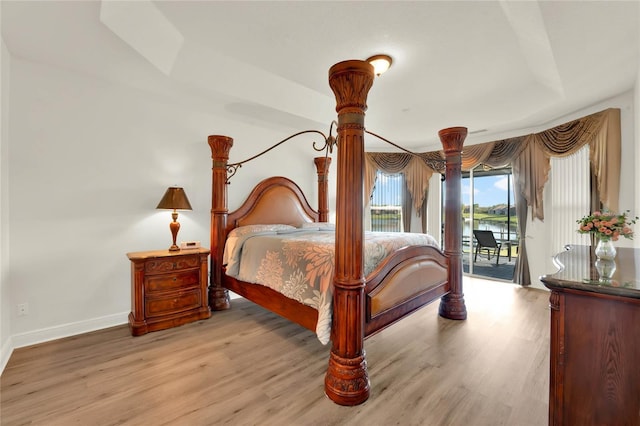 bedroom featuring access to exterior, baseboards, and wood finished floors