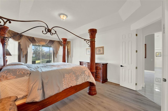 bedroom featuring baseboards, wood finished floors, and access to exterior