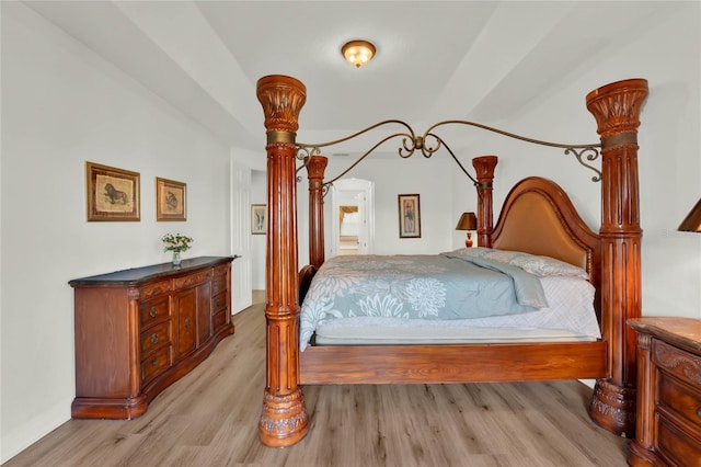 bedroom featuring arched walkways and light wood finished floors