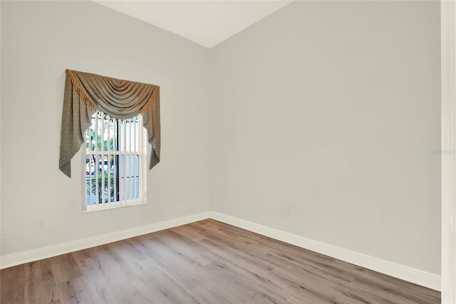 spare room with baseboards and wood finished floors