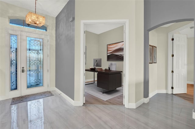 foyer entrance with baseboards, arched walkways, and a chandelier