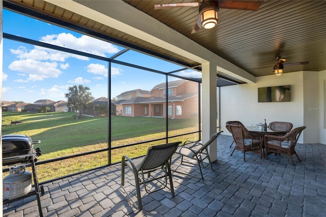 sunroom / solarium featuring a residential view and ceiling fan