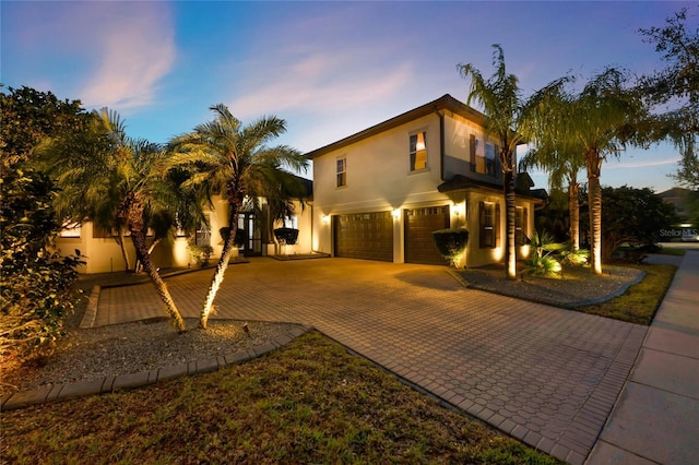 view of front of house featuring stucco siding, an attached garage, and decorative driveway