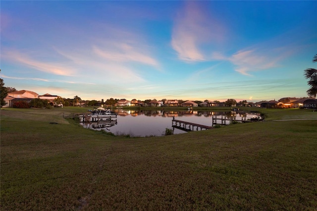 dock area featuring a residential view, a yard, and a water view