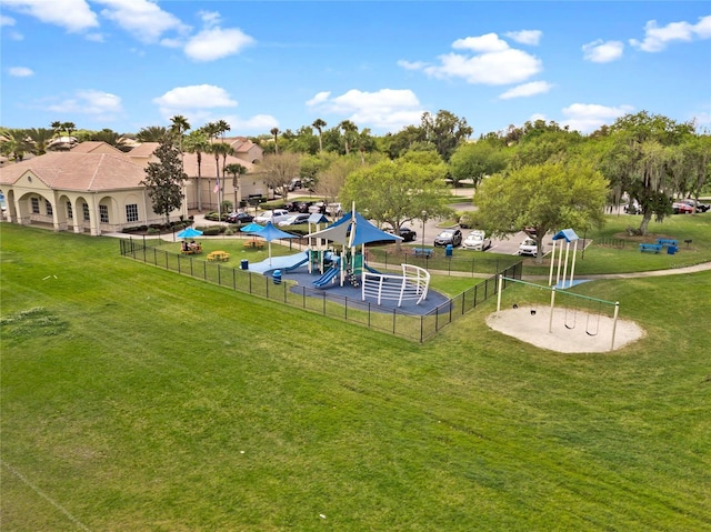 view of property's community with a lawn, playground community, and fence