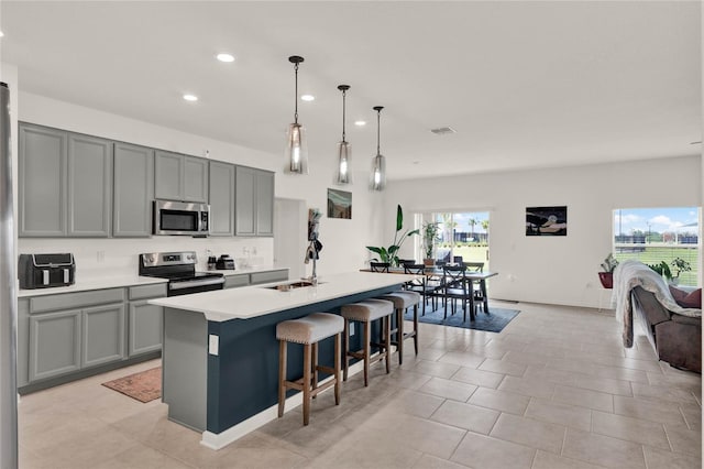 kitchen featuring a sink, appliances with stainless steel finishes, gray cabinets, and light countertops